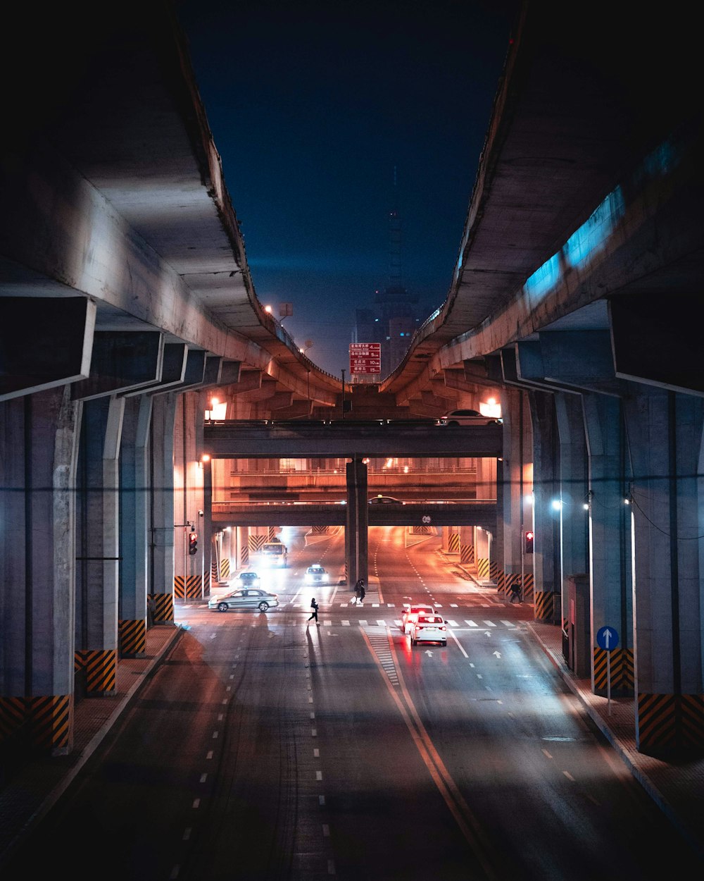 Eine nächtliche Stadtstraße mit Autos, die unter einer Brücke hindurchfahren