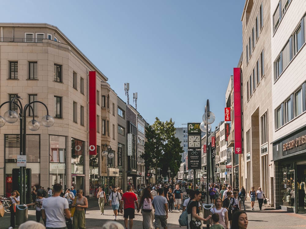 a crowd of people walking down a street next to tall buildings