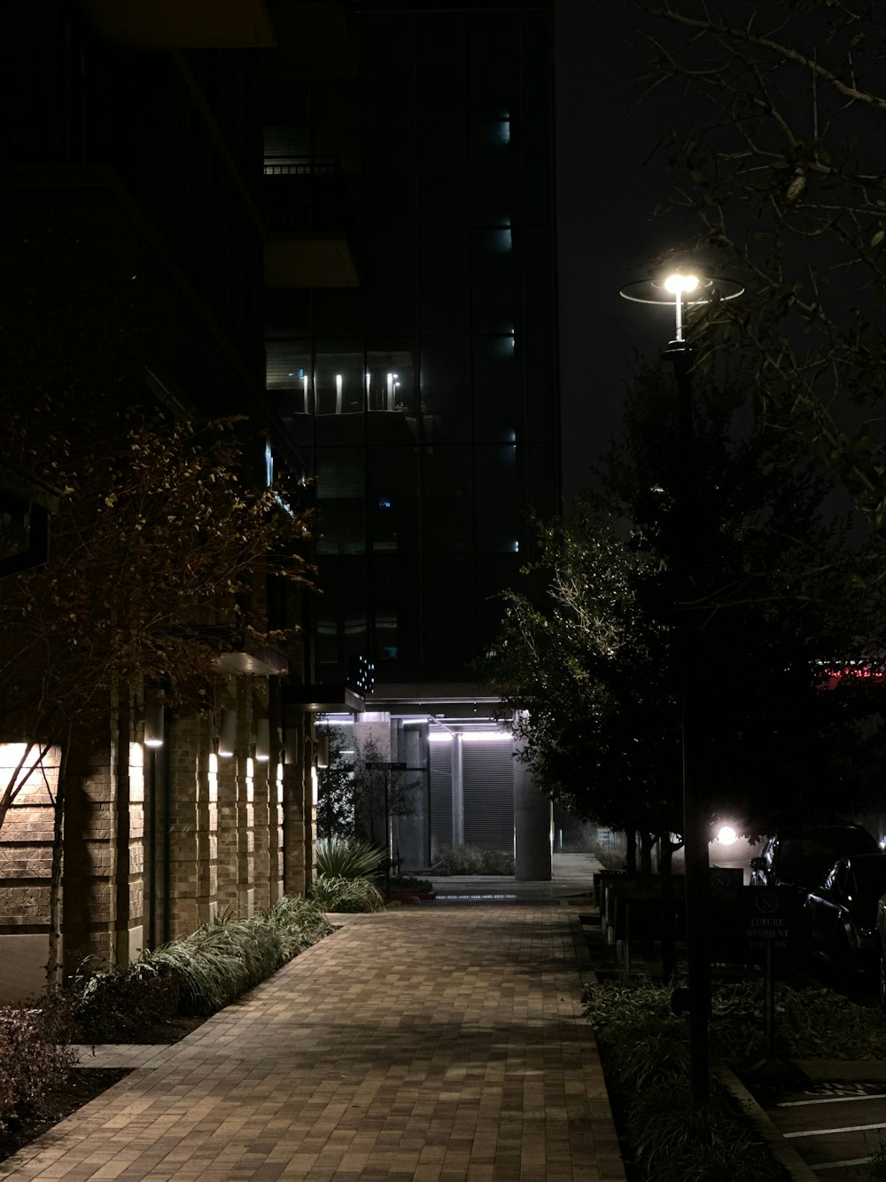 a street at night with a clock tower in the background