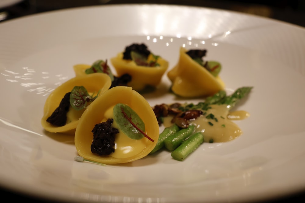 a white plate topped with ravioli and green beans