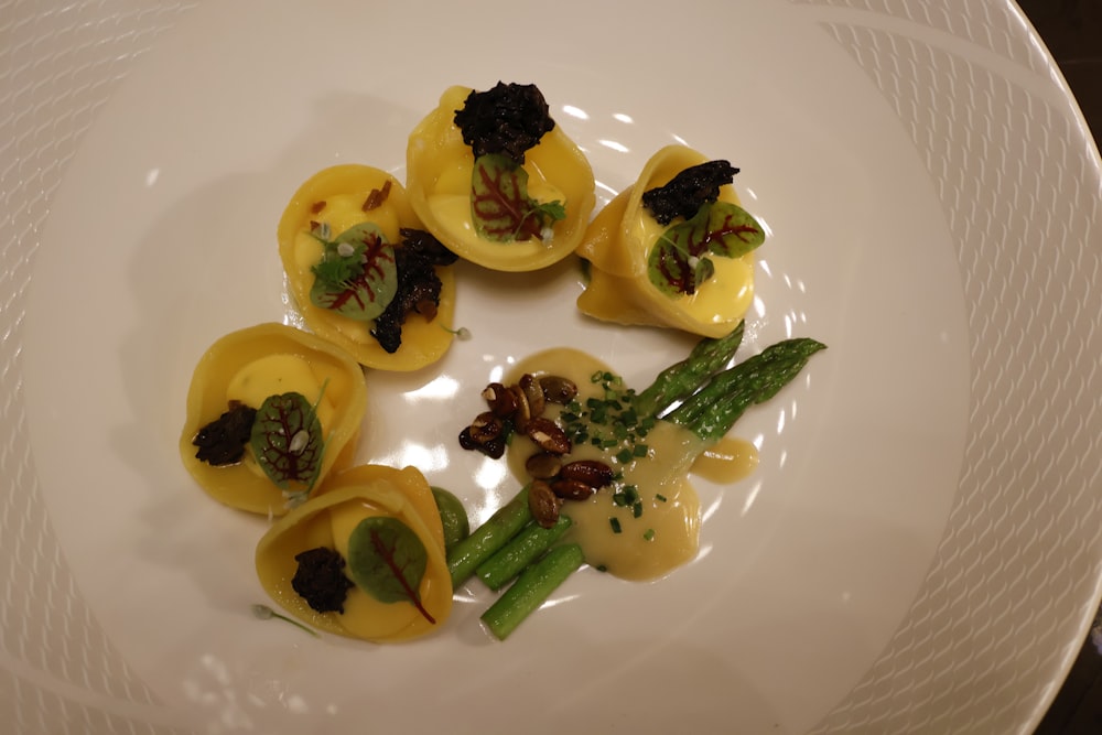 a white plate topped with ravioli and asparagus