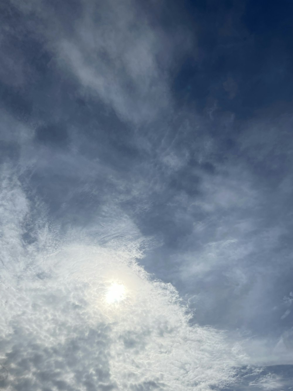 a plane flying through a cloudy blue sky