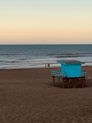 a lifeguard tower on a beach with people in the background