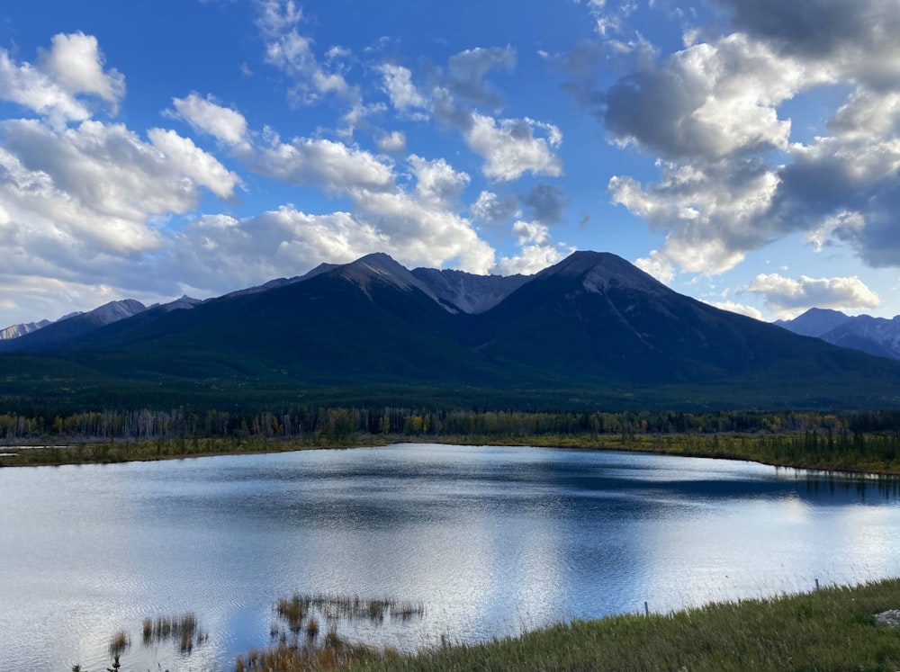 a lake surrounded by mountains under a cloudy sky