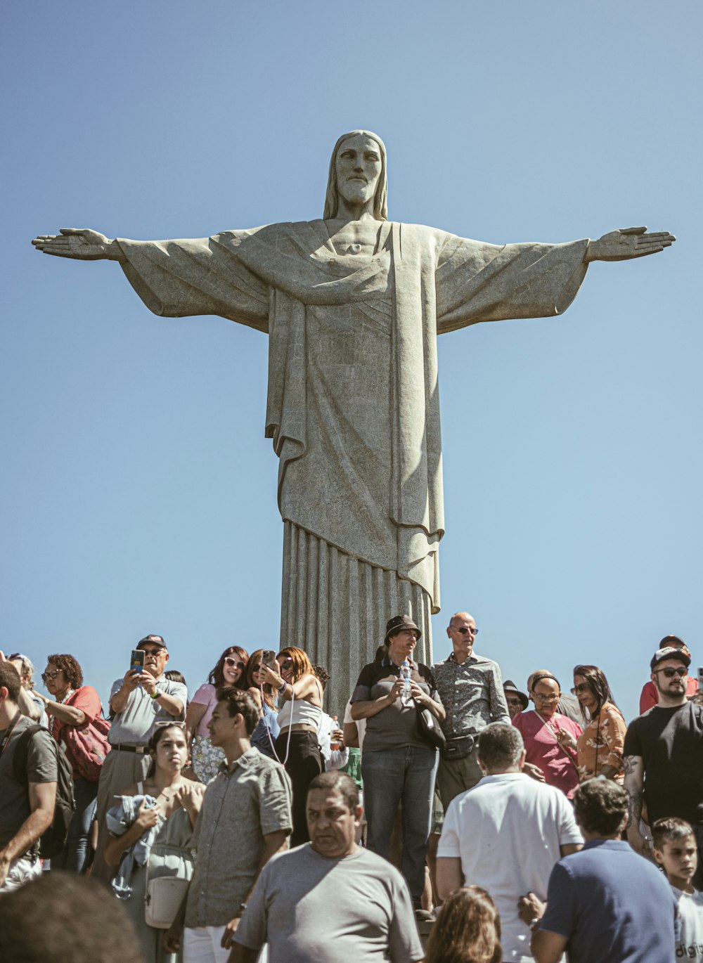 a crowd of people standing around a statue of jesus