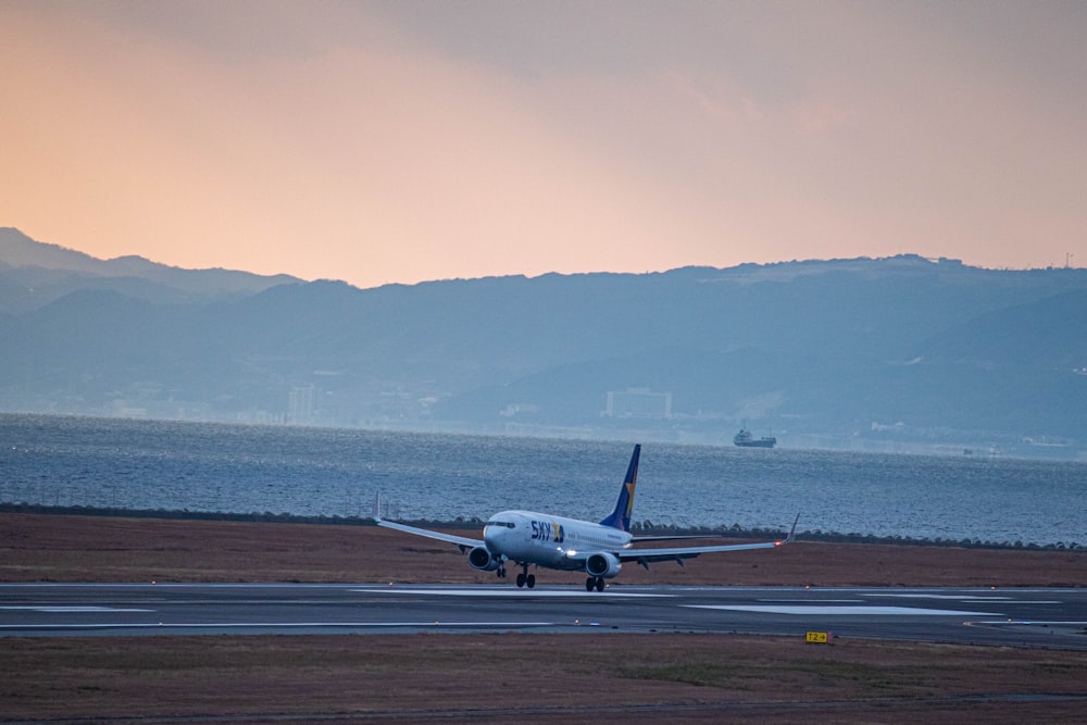 a plane on a runway with mountains in the background