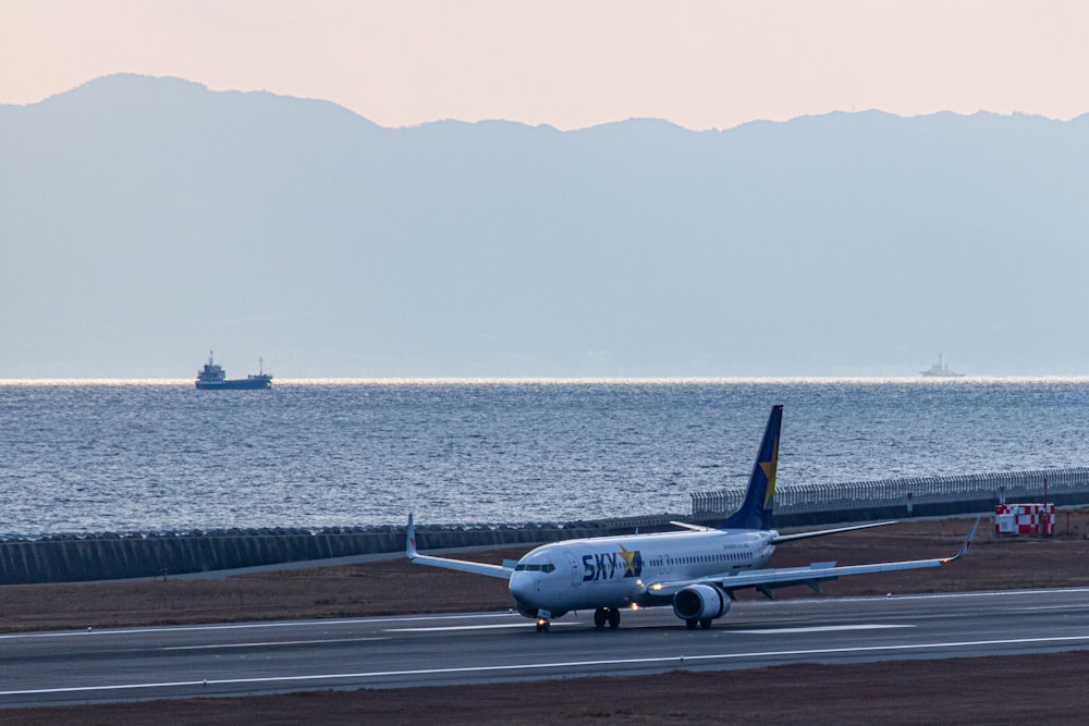 a plane is on the runway near the water