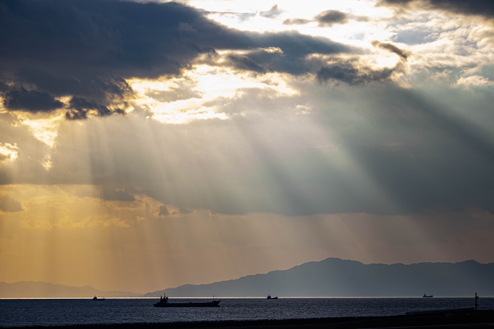 a boat floating on top of a body of water under a cloudy sky