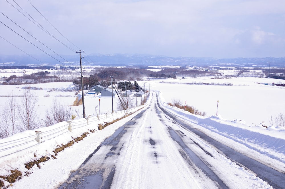 a snow covered road with power lines in the distance