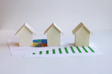 three small houses sitting on top of a piece of paper