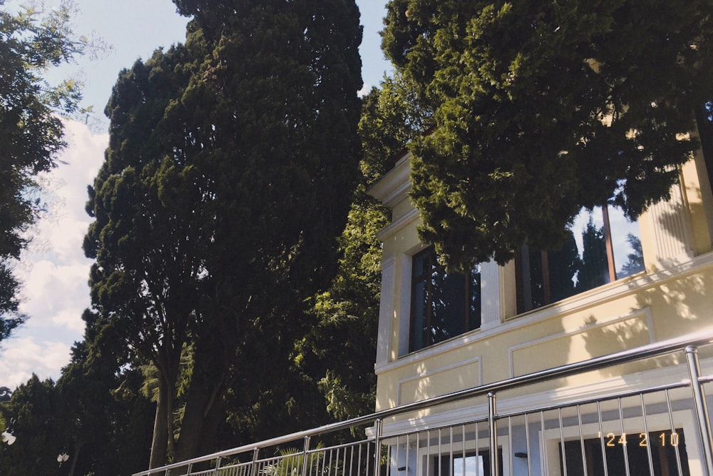 a white house with a gate and trees in the background