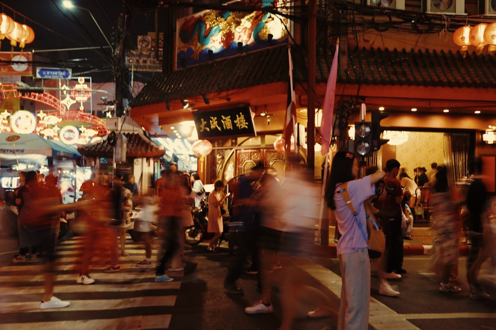 a crowd of people walking across a street at night