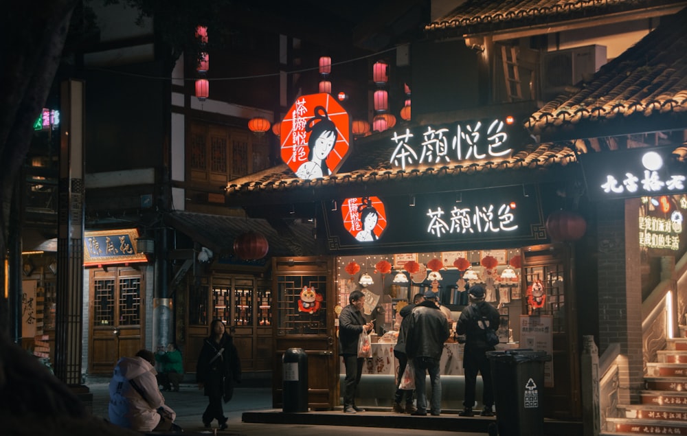 a group of people standing outside of a store at night