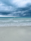 a surfboard is laying on the beach under a cloudy sky