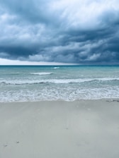 a surfboard is laying on the beach under a cloudy sky