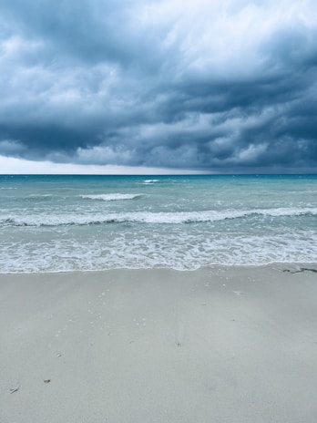 a surfboard is laying on the beach under a cloudy sky