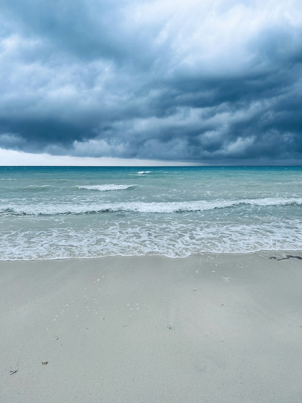 a surfboard is laying on the beach under a cloudy sky