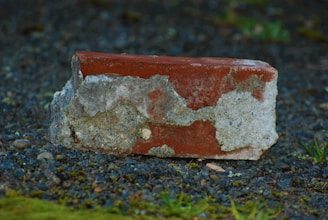 a red and white brick sitting on top of a gravel field