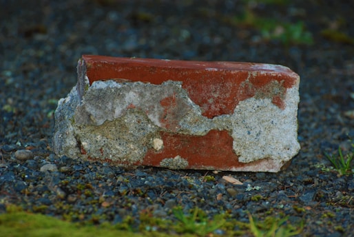 a red and white brick sitting on top of a gravel field