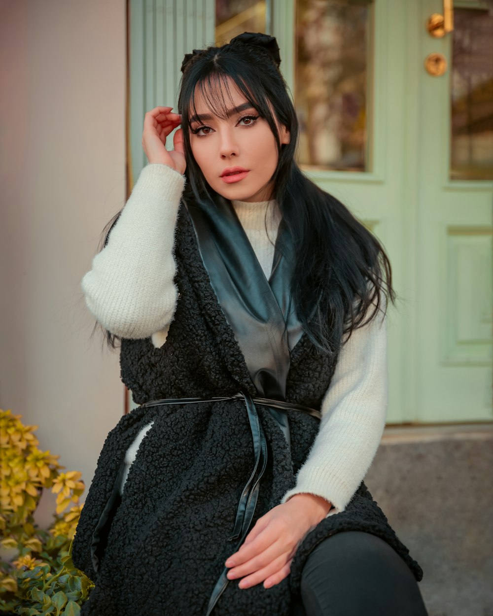 a woman with long black hair wearing a black vest