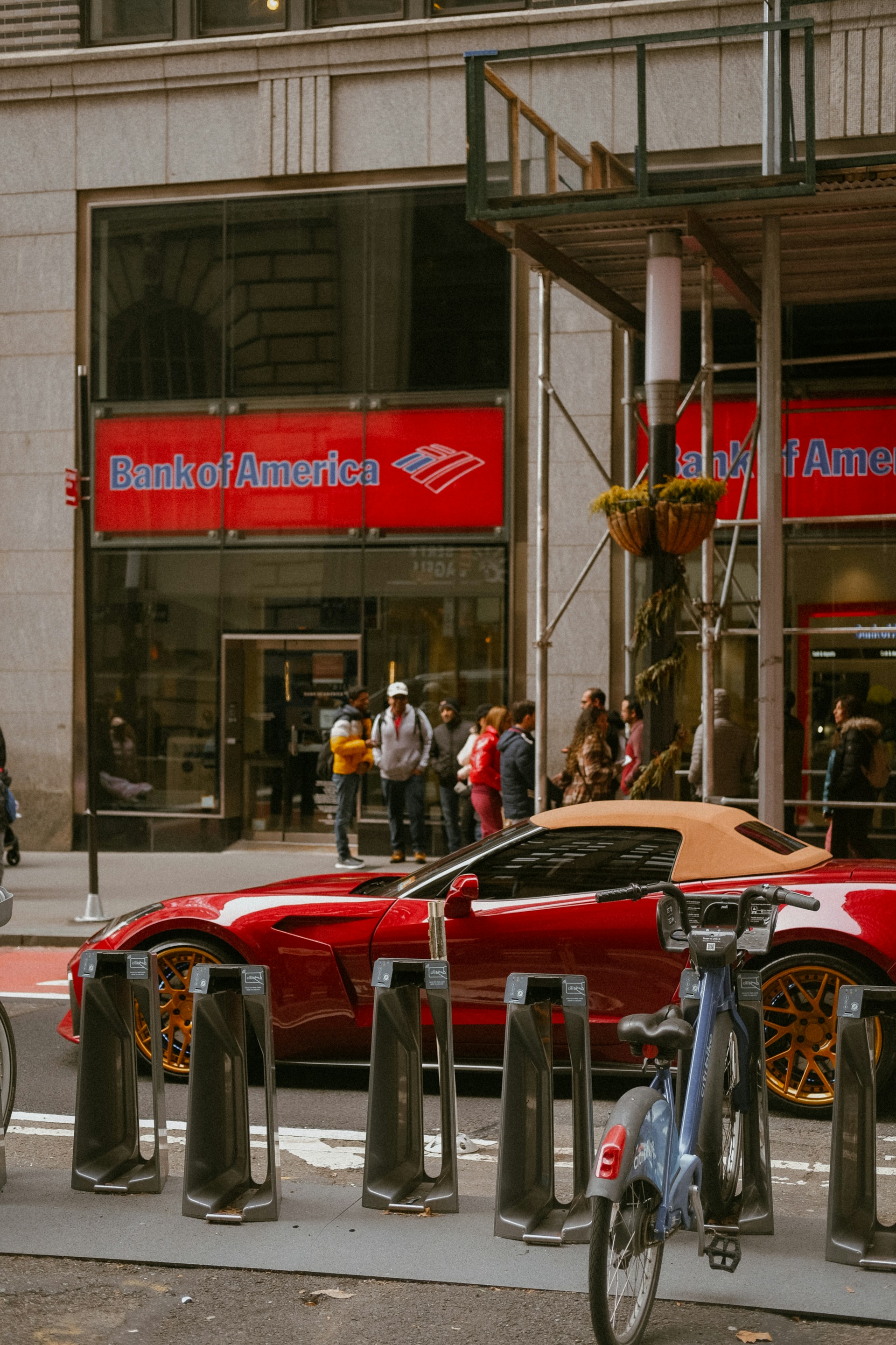 a red sports car is parked in front of a bank of america