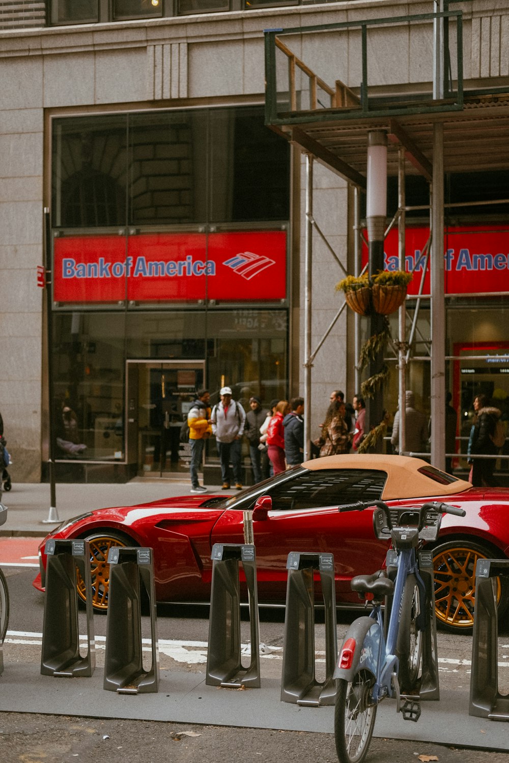 a red sports car is parked in front of a bank of america