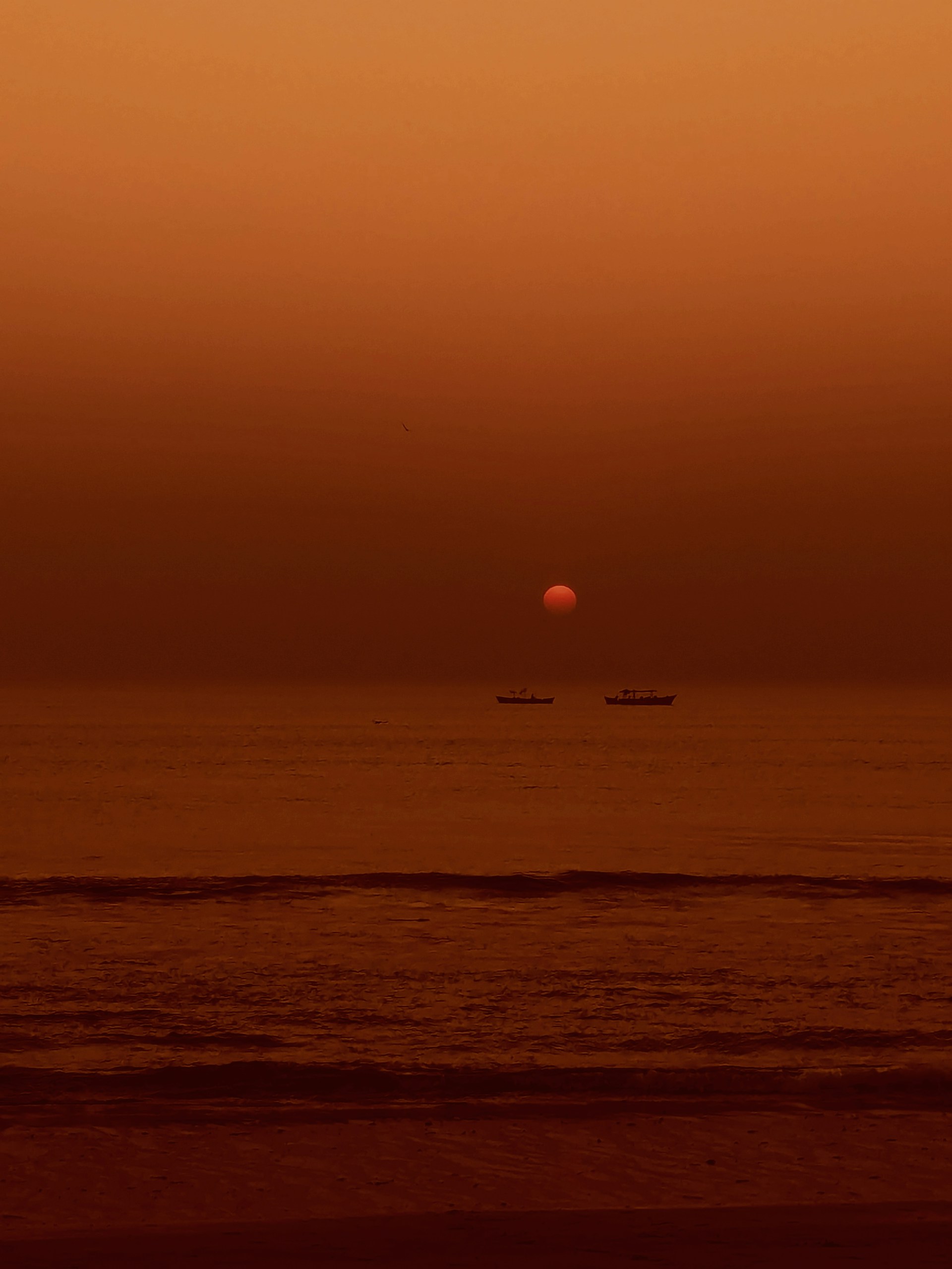 a sunset over the ocean with a boat in the distance