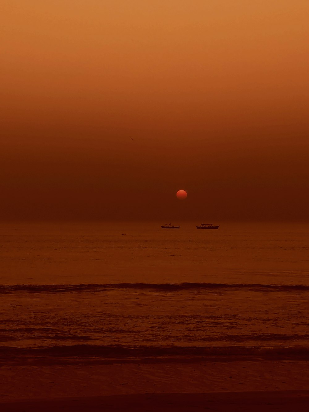 a sunset over the ocean with a boat in the distance