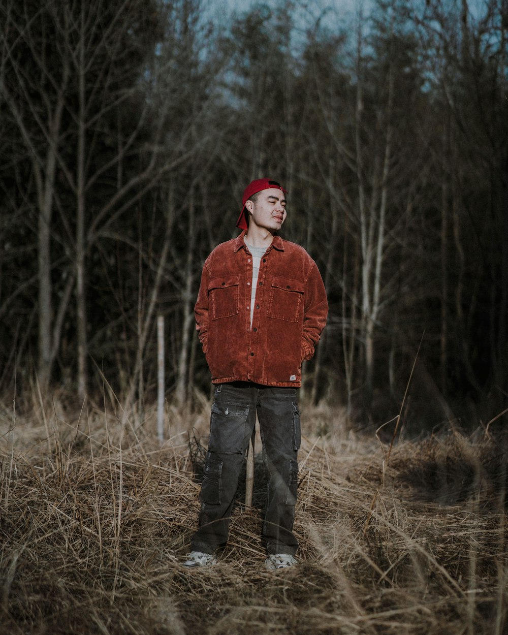 a man standing in a field with trees in the background