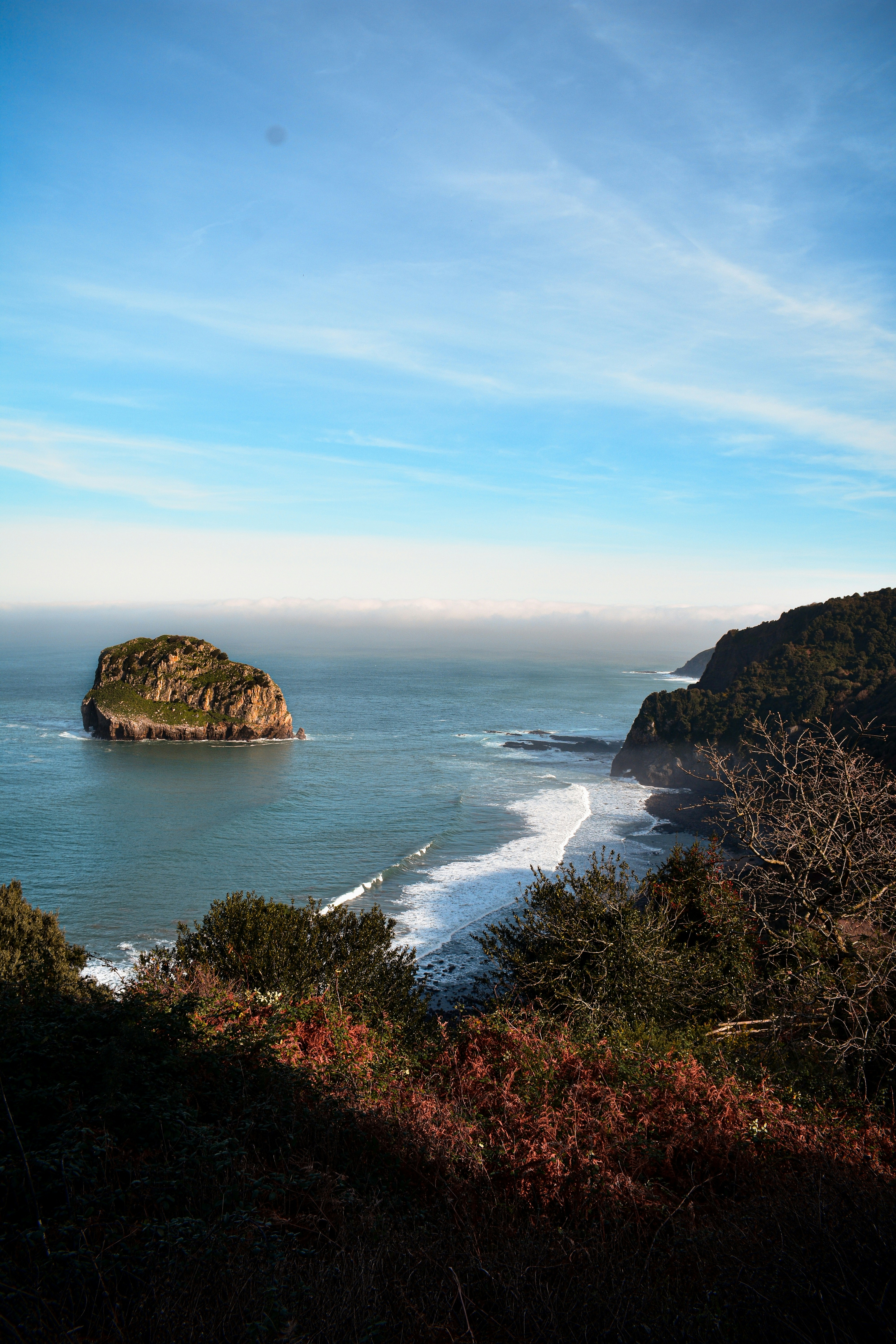 una gran masa de agua junto a una exuberante ladera verde