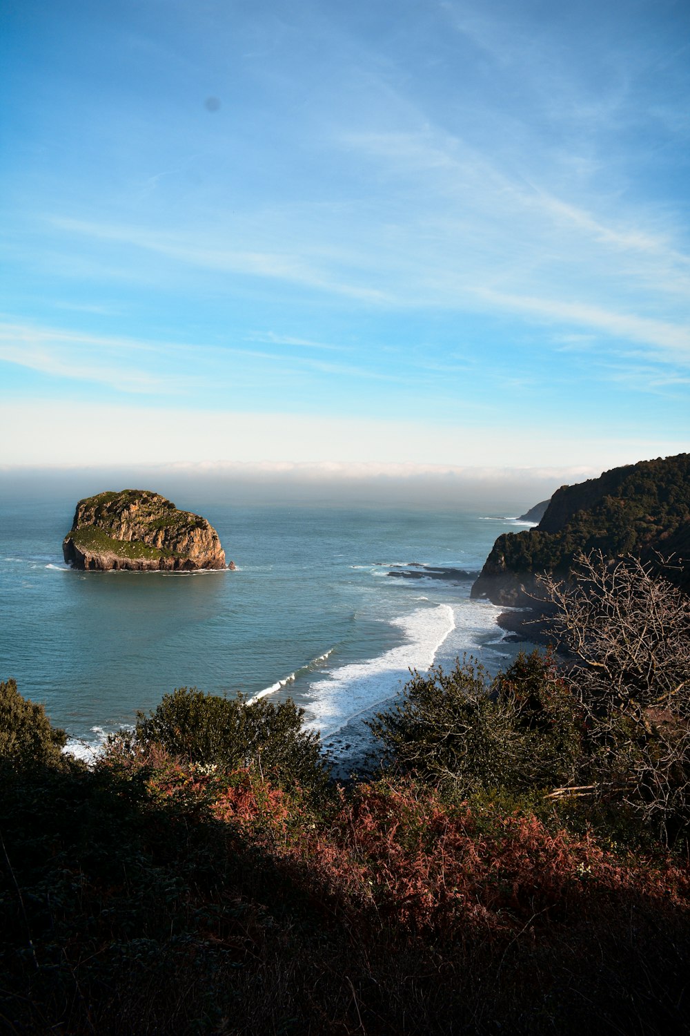 a large body of water sitting next to a lush green hillside