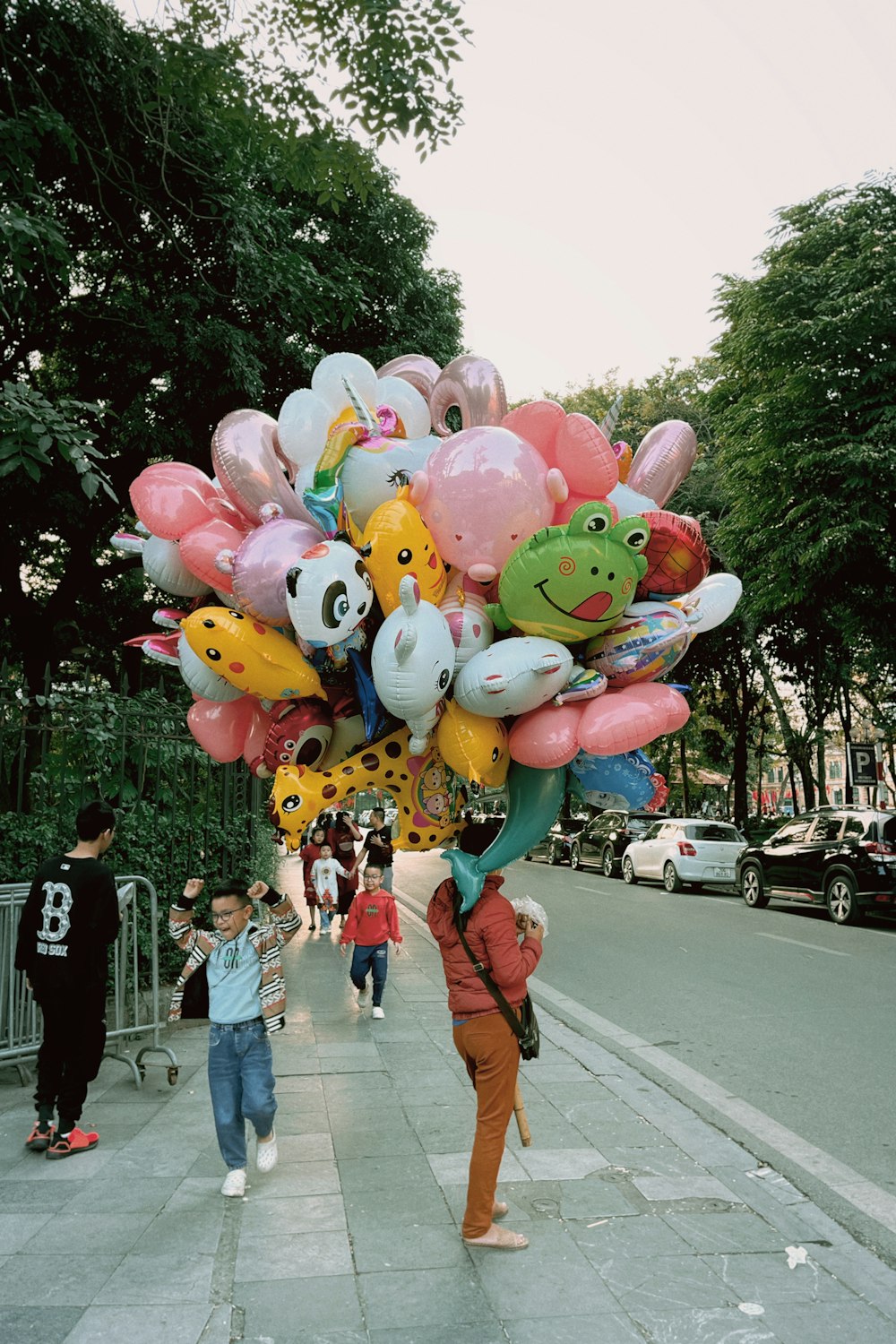 a person holding a bunch of balloons on a sidewalk