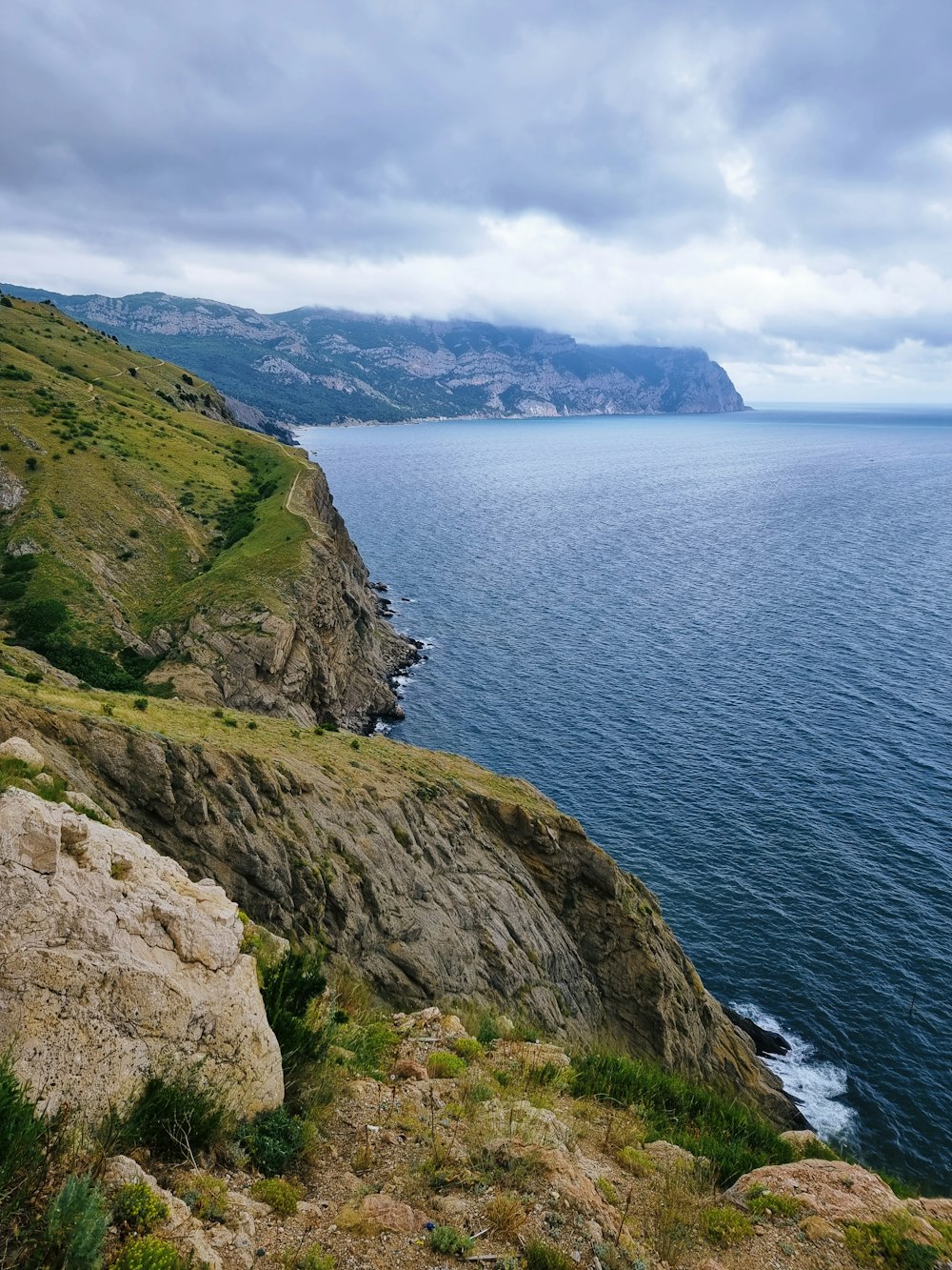 a large body of water sitting next to a lush green hillside