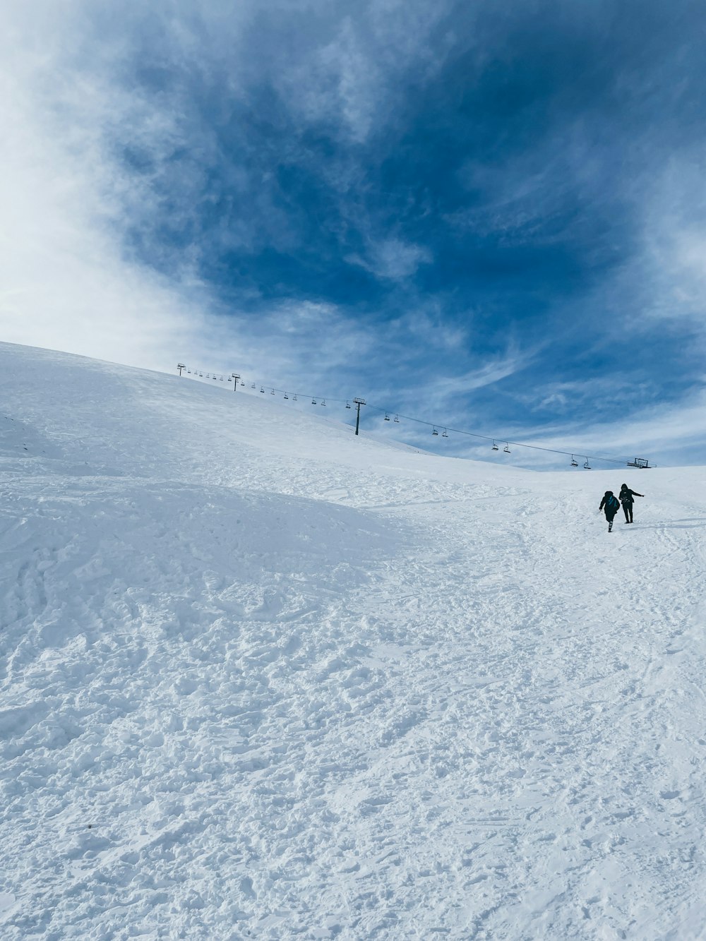 a couple of people riding skis down a snow covered slope