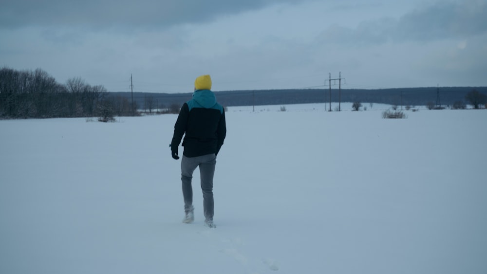 a man walking through a snow covered field