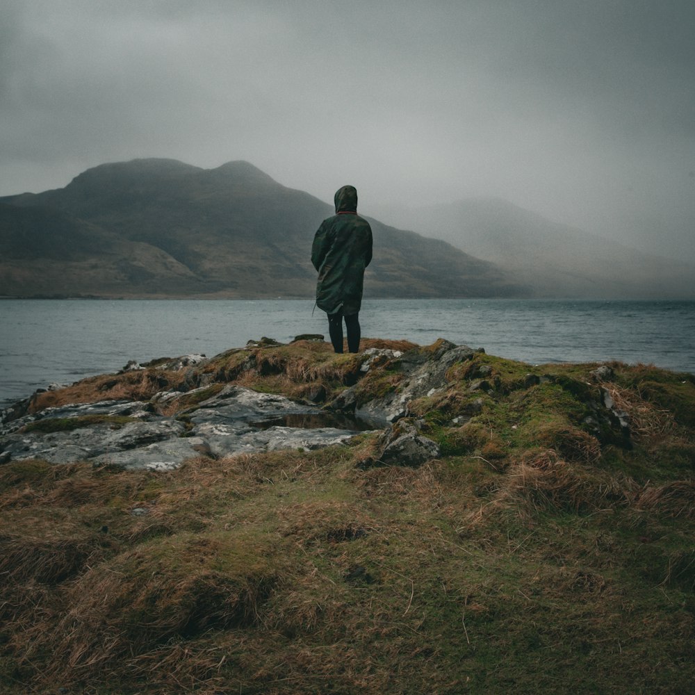 a man standing on top of a lush green hillside