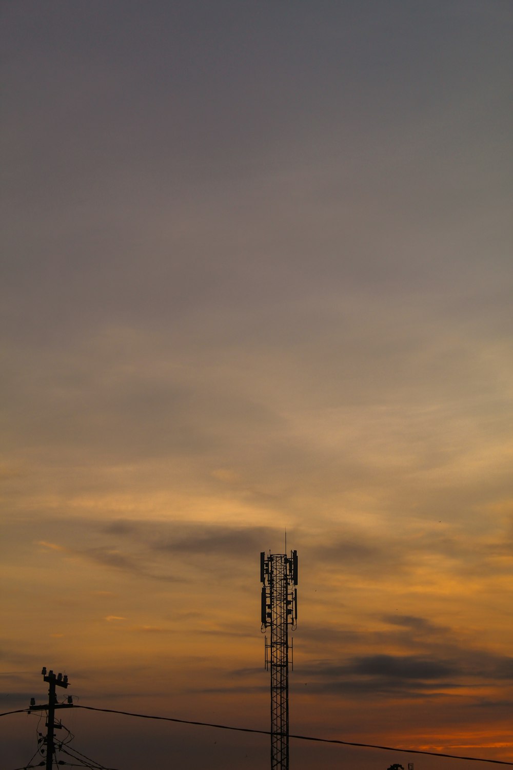 the sun is setting behind a radio tower