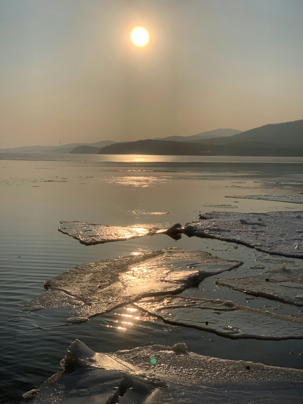 the sun is shining over the water and ice