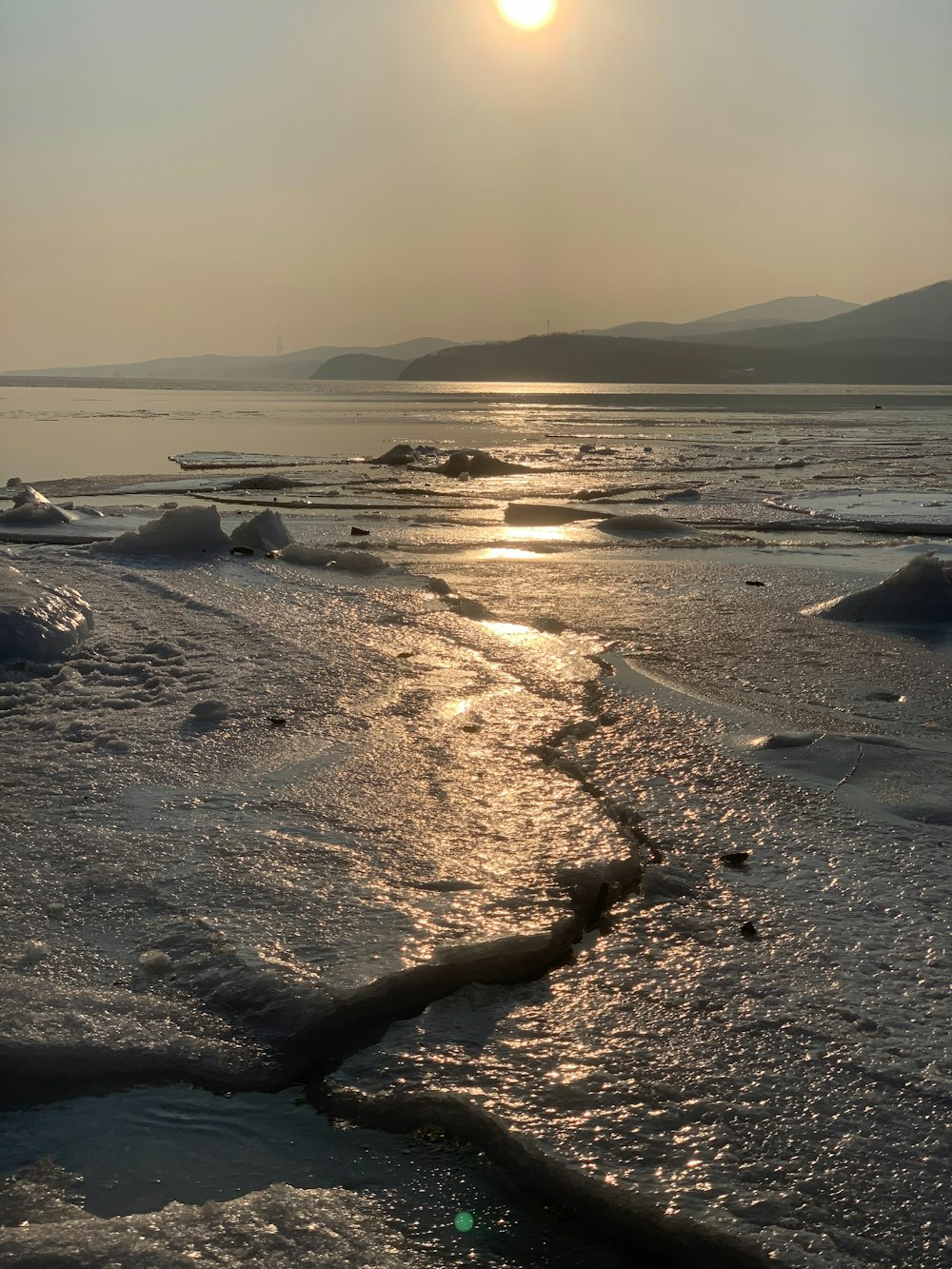 the sun is shining over the water and ice