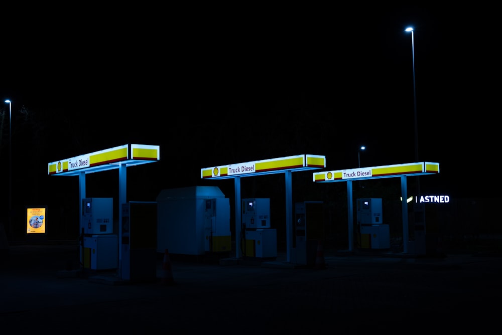 gas pumps lit up at night in a parking lot