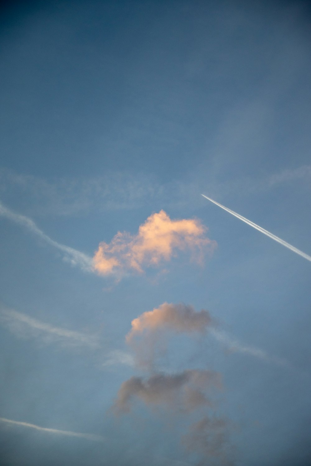 a plane flying through a cloudy blue sky