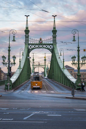 a yellow bus driving across a green bridge