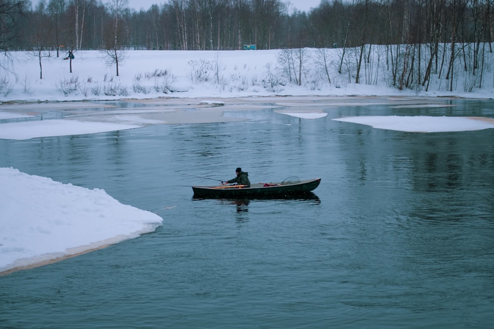 a man in a canoe on a frozen river