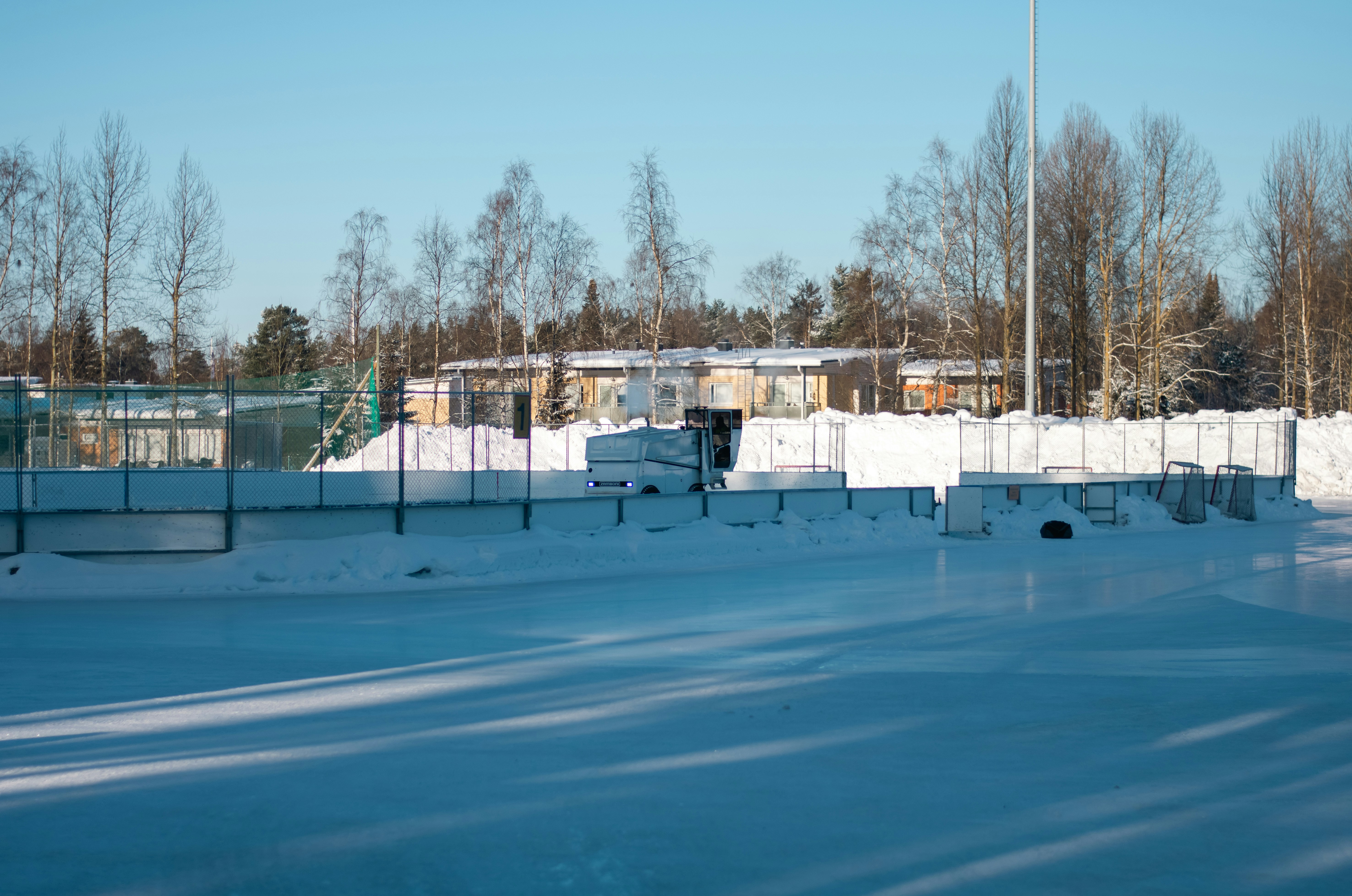 a tennis court covered in snow with trees in the background