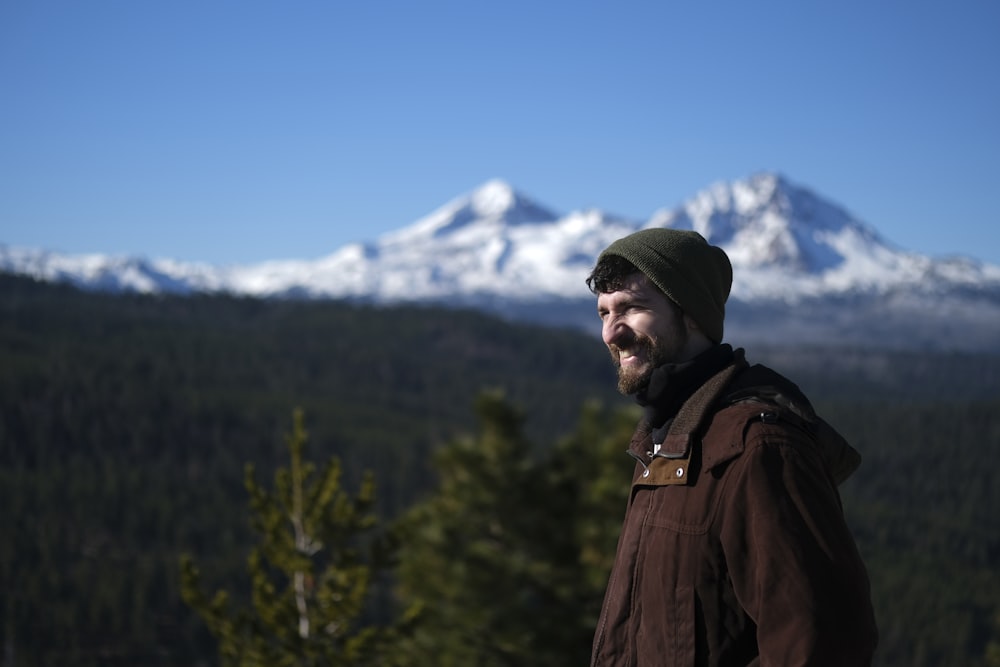 a man with a beard standing in front of a mountain
