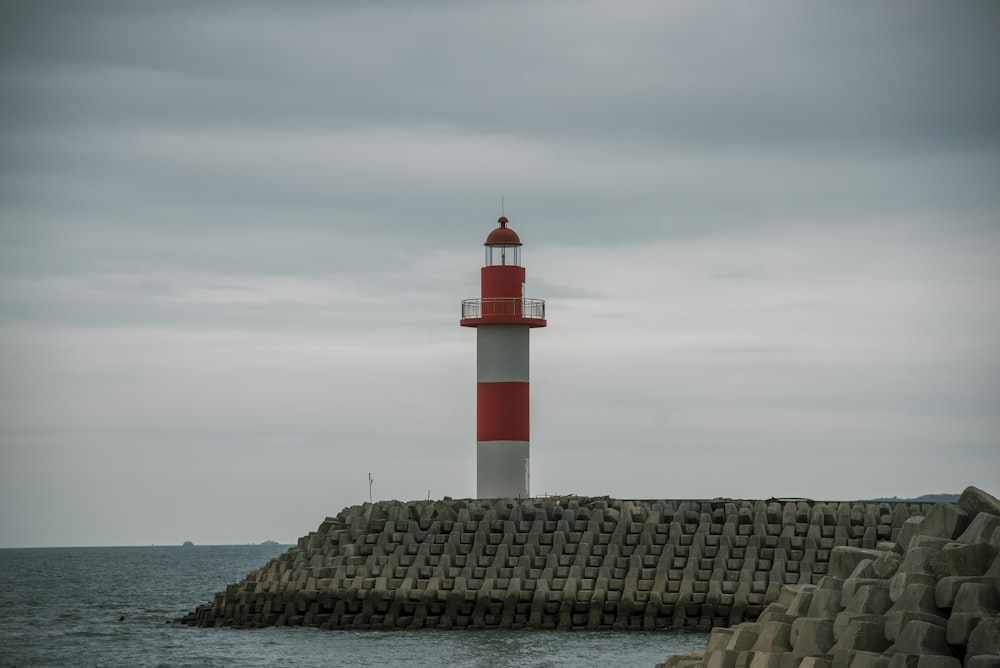 a red and white light house sitting on top of a pier