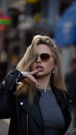 a woman in a leather jacket smoking a cigarette