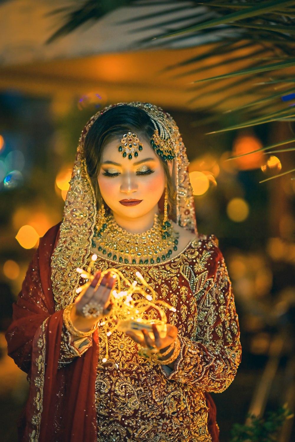 a woman dressed in traditional indian garb holding a lit candle
