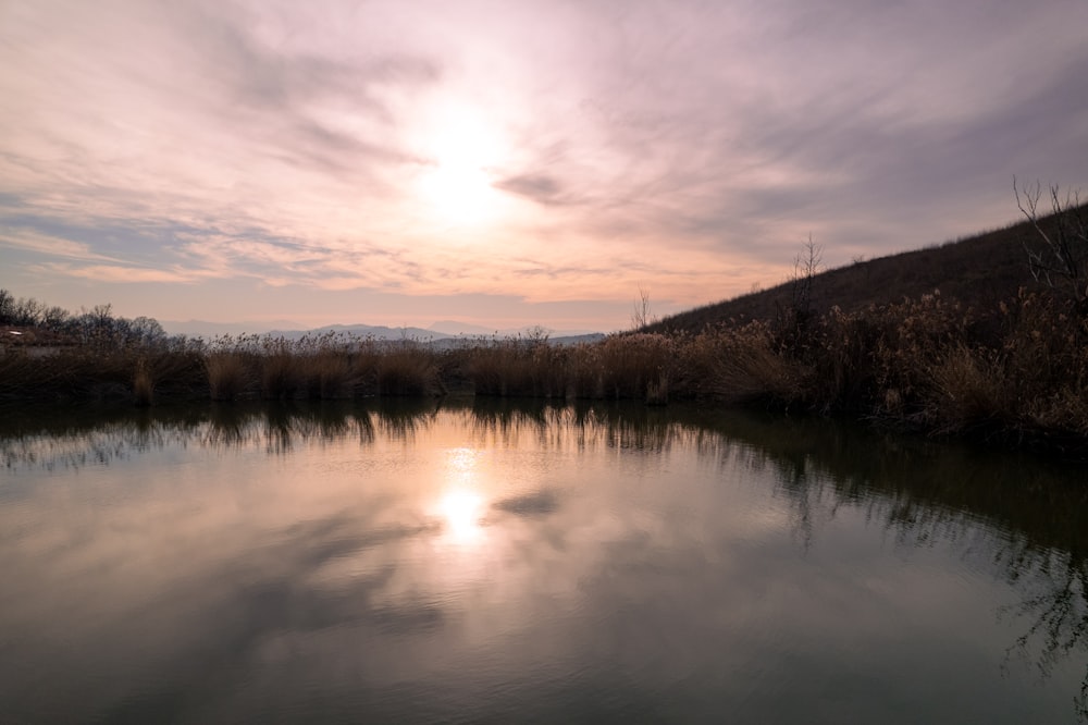 a body of water with a hill in the background