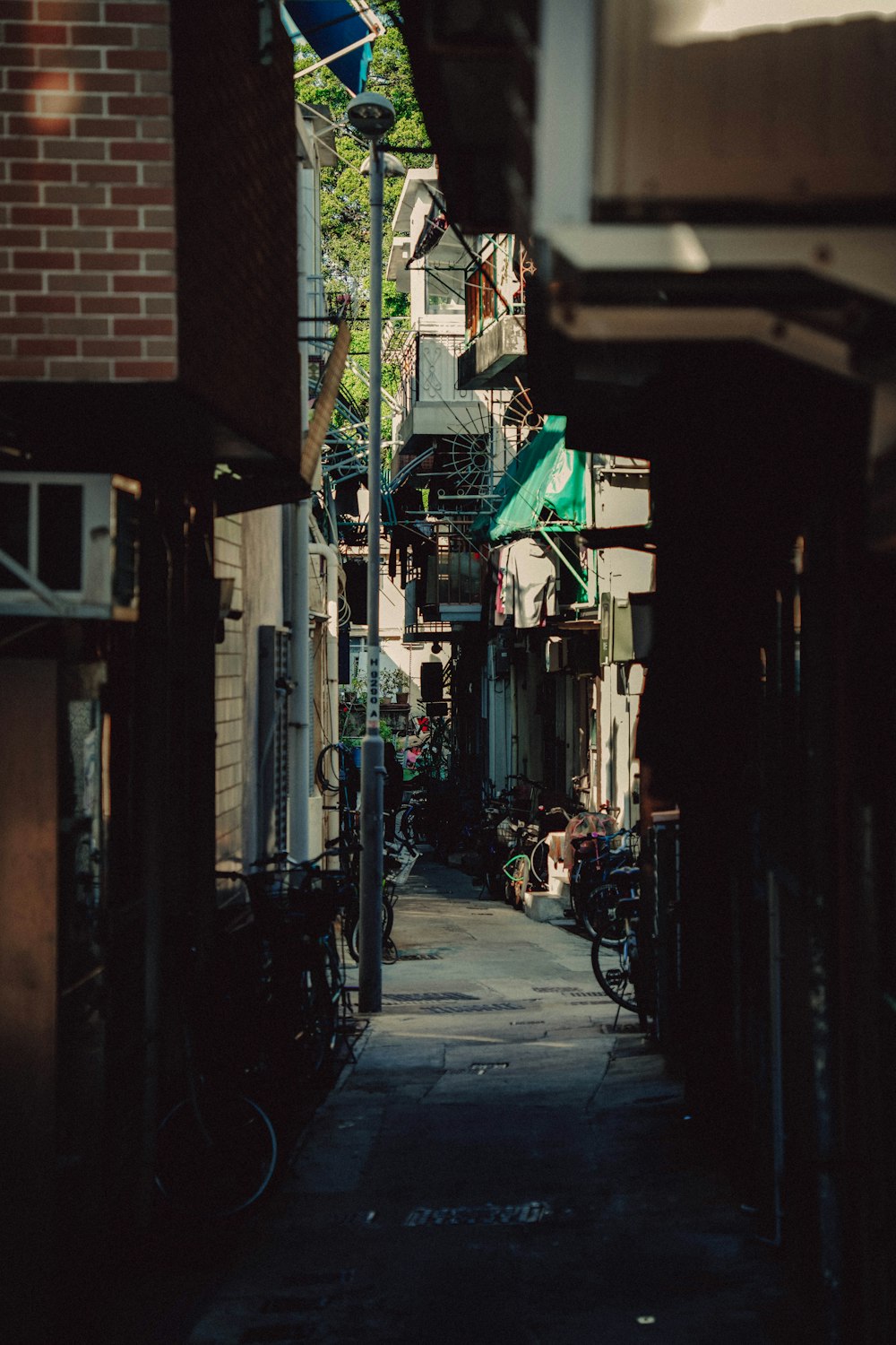 a narrow alley way with buildings and a green awning